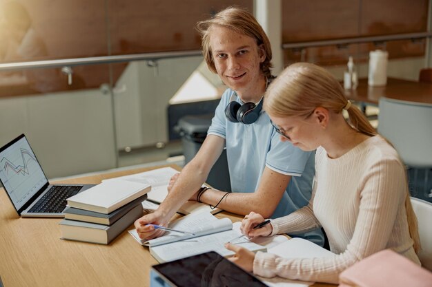 Dos estudiantes talentosos trabajando juntos en un proyecto universitario sentados en la biblioteca