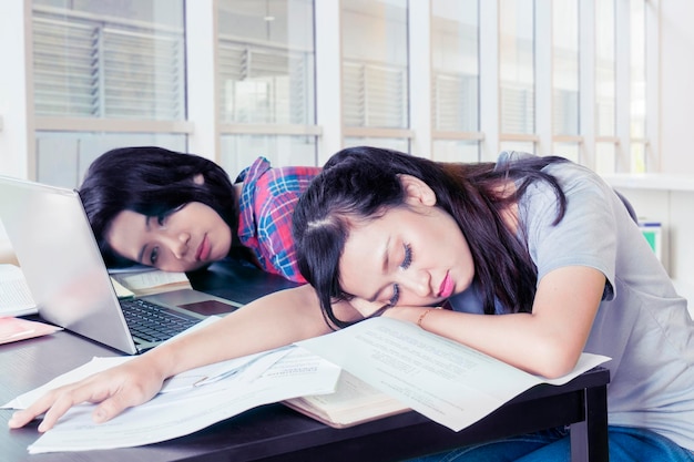 Dos estudiantes universitarios femeninos durmiendo en el aula