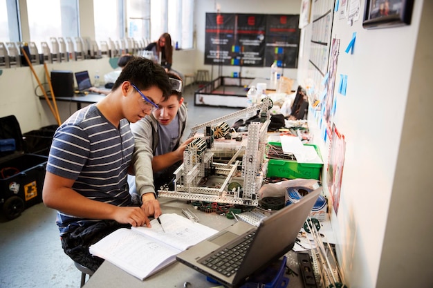 Dos estudiantes universitarios con una máquina de construcción de portátiles en la clase de ciencias, robótica o ingeniería