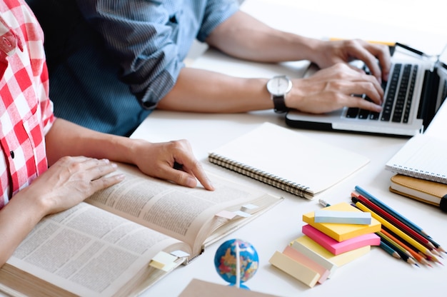 Dos estudiantes universitarios que leen un libro o hacen la tarea juntos en una clase u hogar