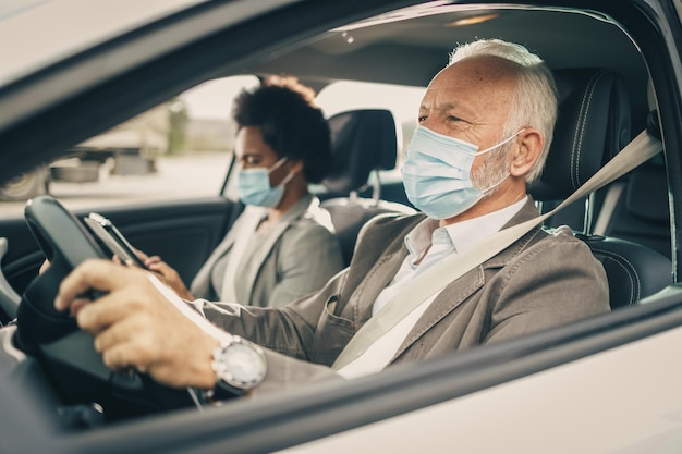 Dos exitosos empresarios multiétnicos con máscara protectora en su viaje matutino durante la pandemia de COVID-19.