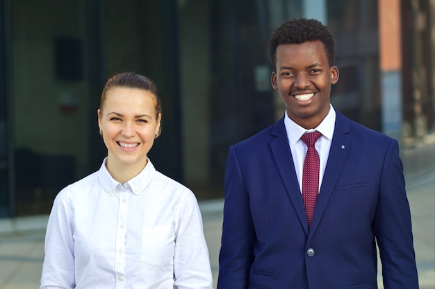 Dos felices estudiantes o trabajadores jóvenes multinacionales sonriendo. Hombre de negocios afroamericano negro africano y mujer blanca trabajando juntos.
