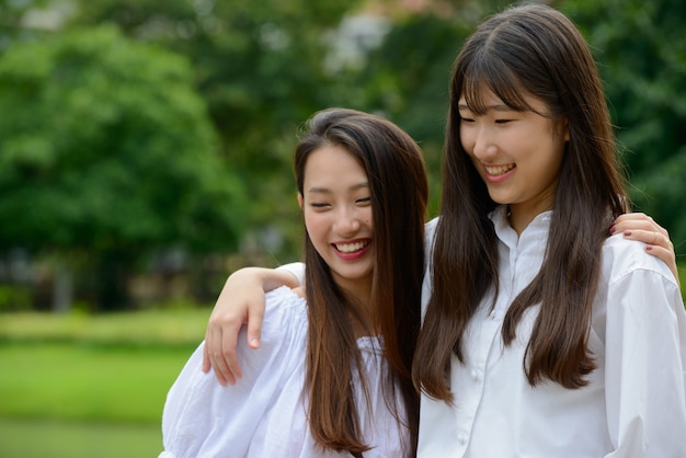 Dos felices jóvenes hermosas mujeres adolescentes asiáticas unir en el parque