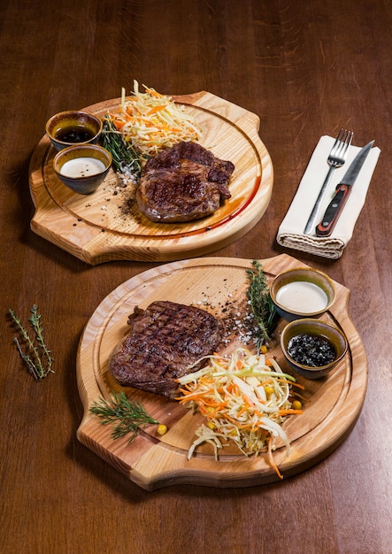 Dos filetes de carne con verduras y vegetación en una mesa de madera en un restaurante de lujo