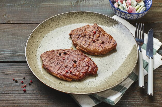 Dos filetes de chuletón a la parrilla, especias y ensalada de tomate y pepino con crema agria