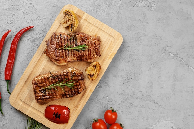 Dos filetes de res a la parrilla sobre tabla de madera, vista superior