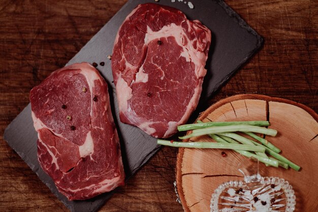 Foto dos filetes de ribeye con sal y pimienta en el fondo de la tabla de corte negra