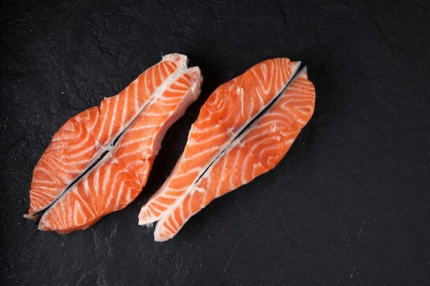 Dos filetes de salmón crudo sobre una textura negra