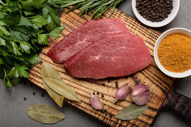 Dos filetes de ternera cruda con especias sobre una tabla para cortar en negro