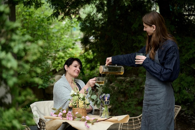 Dos floristas mamá e hija bebiendo té en el jardín