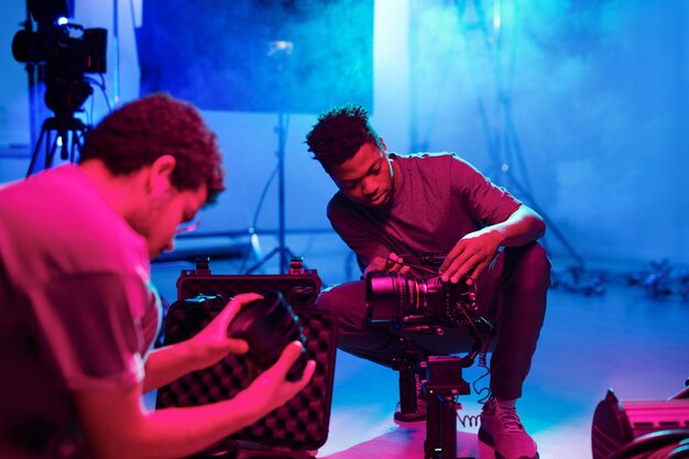 Foto dos fotógrafos profesionales configurando cámaras antes de disparar mientras trabajan en el estudio