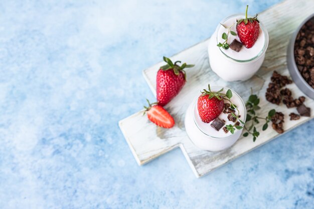 Dos frascos con granola de chocolate y yogur y fresas frescas