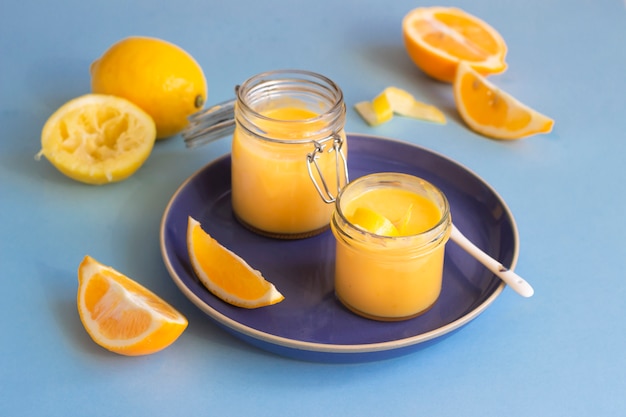 Dos frascos de requesón casero y limones frescos en un plato de cerámica azul