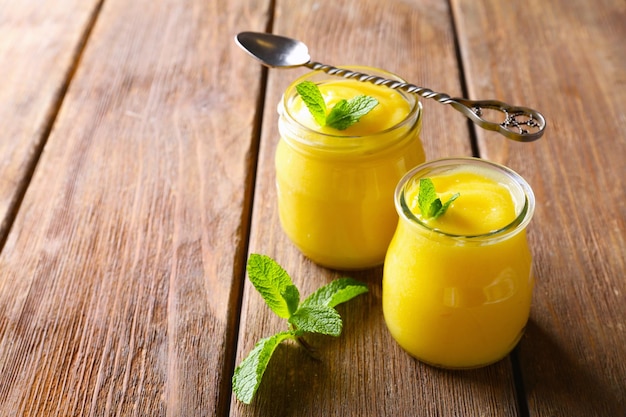 Dos frascos de vidrio con deliciosa cuajada de limón sobre mesa de madera