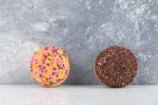 Dos galletas frescas con chispitas de colores colocadas sobre la superficie de piedra