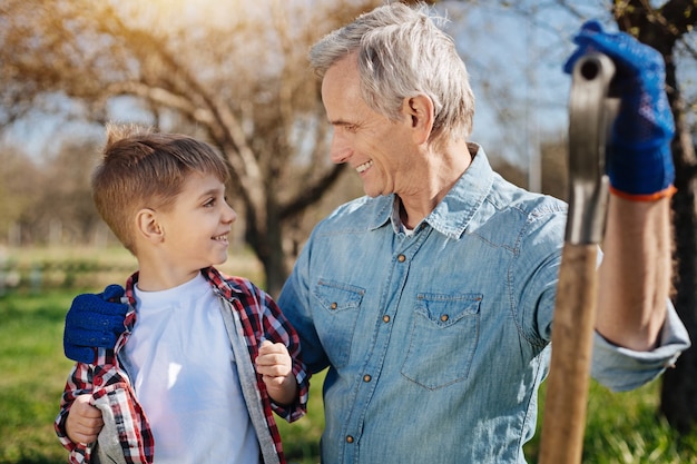 Foto dos generaciones masculinas pasar tiempo libre al aire libre en un jardín y mirarse mientras se toma un descanso