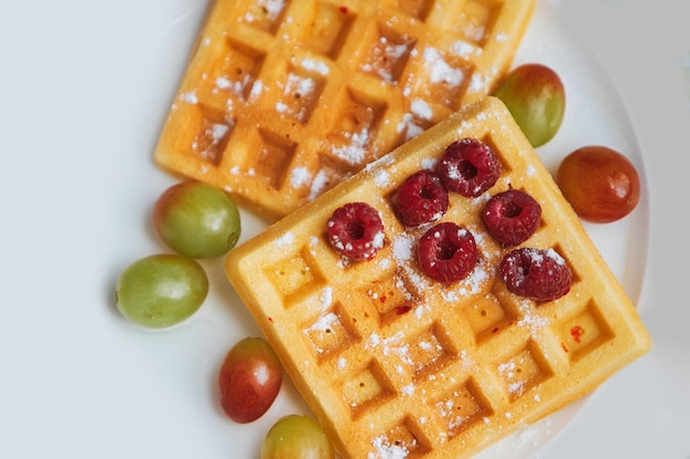 Dos gofres con uvas y uno con un fruto rojo encima.