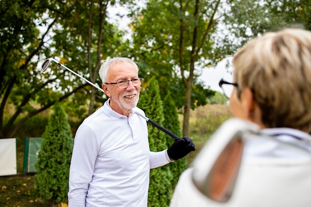 Dos golfistas mayores que tienen una conversación antes del entrenamiento de golf.