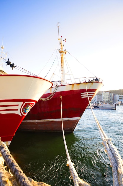 Dos grandes barcos de pesca amarrados en el puerto al atardecer