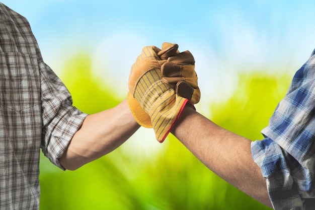 Dos granjeros masculinos con guantes dándose la mano