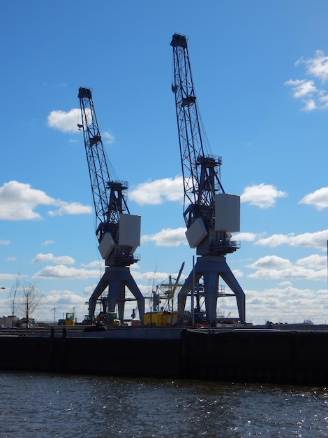 Dos grúas están paradas una al lado de la otra en un muelle.