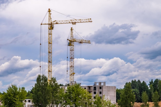 Dos grúas torre trabajando en la construcción con nubes onduladas rizadas y esponjosas de tormenta como fondo