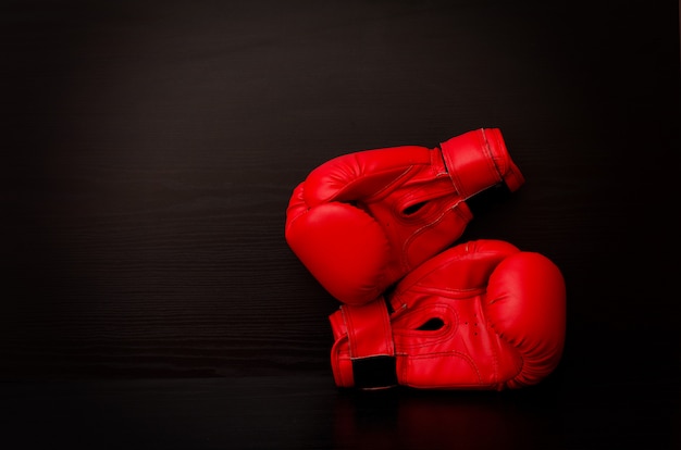 Dos guantes de boxeo rojos en el lateral del bastidor sobre un fondo negro.