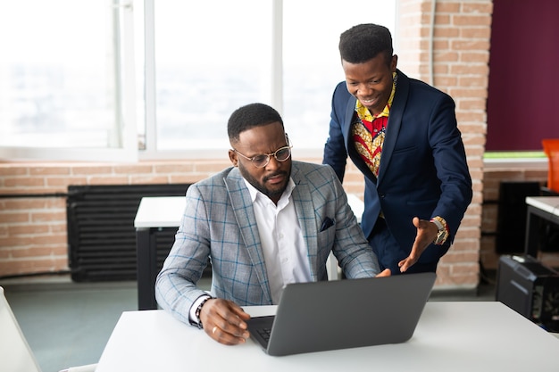 Dos guapos jóvenes africanos en la mesa con un portátil