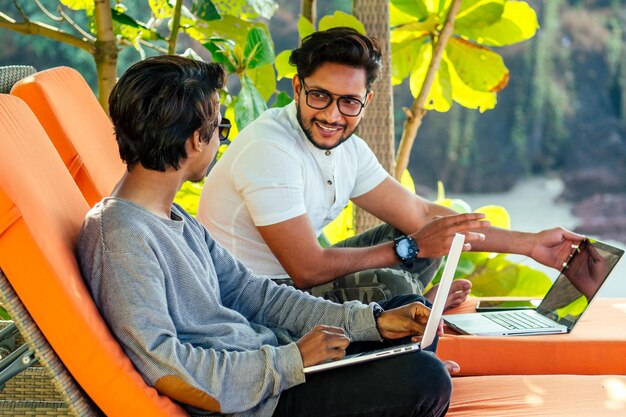 dos guapos y jóvenes indios exitosos que trabajan de forma independiente navegando a distancia con una computadora portátil