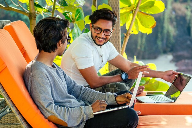 dos guapos y jóvenes indios exitosos que trabajan de forma independiente navegando a distancia con una computadora portátil