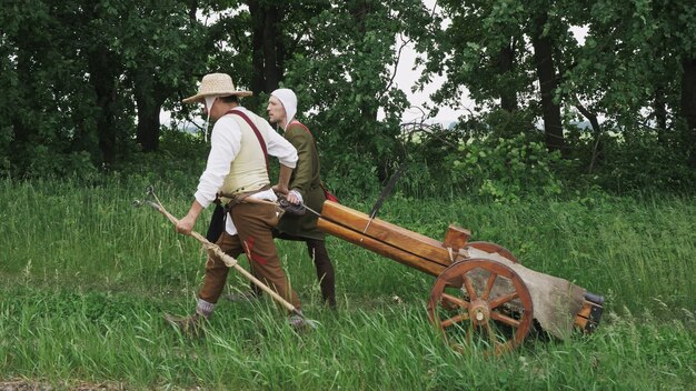 Dos guerreros arrastran un cañón por un sendero del bosque. Reconstrucción histórica