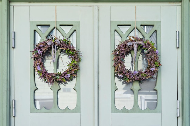 Dos guirnaldas hechas de brezo y otras hierbas del bosque con cinta en la puerta de la casa