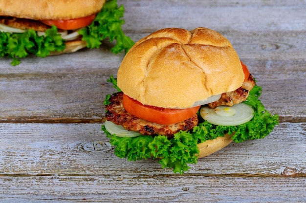 Dos hamburguesas a la parrilla caseras con carne de res, cebolla, lechuga de tomate y queso.