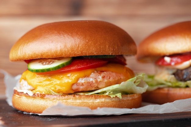 Dos hamburguesas en tablero de madera en mesa gris