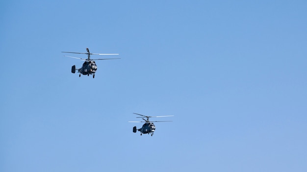 Dos helicópteros militares que vuelan en un cielo azul brillante mientras realizan un vuelo de demostración, el equipo acrobático realiza un vuelo en la exhibición aérea, espacio de copia