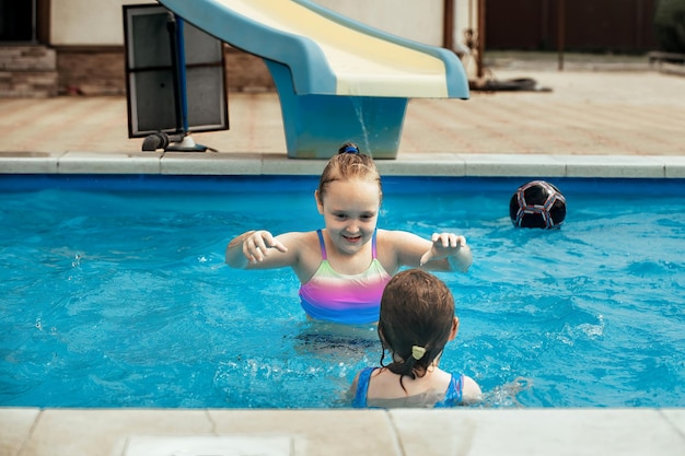 dos hermanas alegres juegan en el agua de la piscina en verano