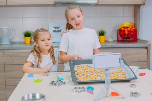 Dos hermanas blogueras están haciendo galletas y filmando videos de capacitación en un teléfono inteligente.