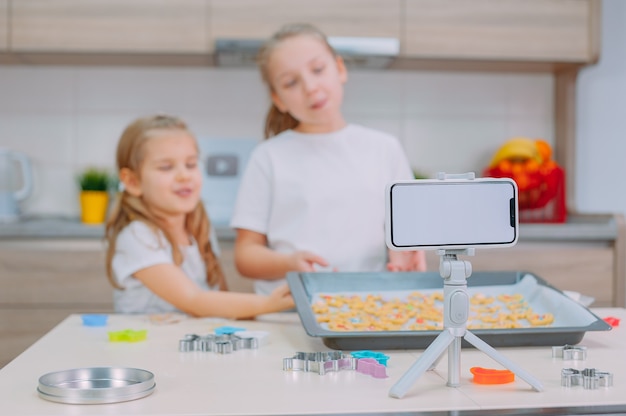 Dos hermanas blogueras están haciendo galletas y filmando videos de capacitación en un teléfono inteligente.