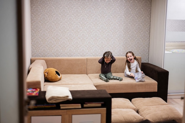 Dos hermanas en casa en el sofá riéndose a carcajadas juntas