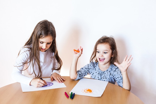 Dos hermanas dibujando con lápices de colores en la hoja de papel. Concepto de arte creativo