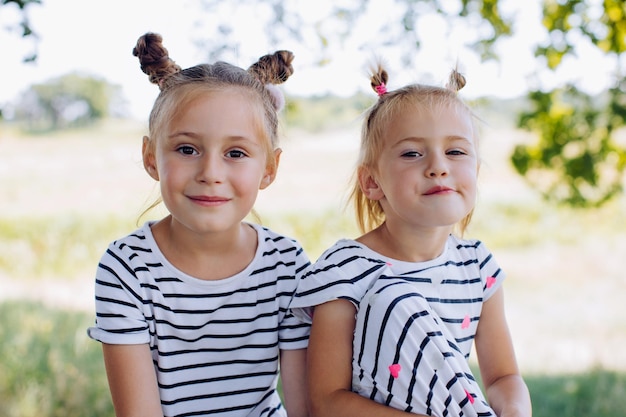 Dos hermanas divertidas miran la cámara en un parque de verano al aire libre