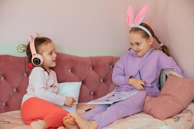 dos hermanas se divierten en casa, dibujan un conejito y escuchan música con auriculares