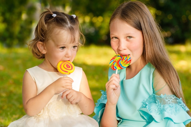 Dos hermanas están sentadas en el césped del parque con paletas de colores