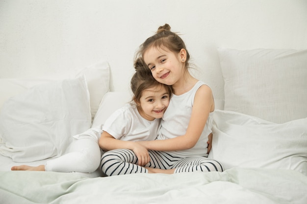 Dos hermanas felices abrazándose en pijama antes de irse a la cama. El concepto de valores familiares y amistad de los niños.