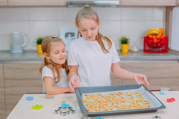 Dos hermanas hacen galletas caseras en la cocina.