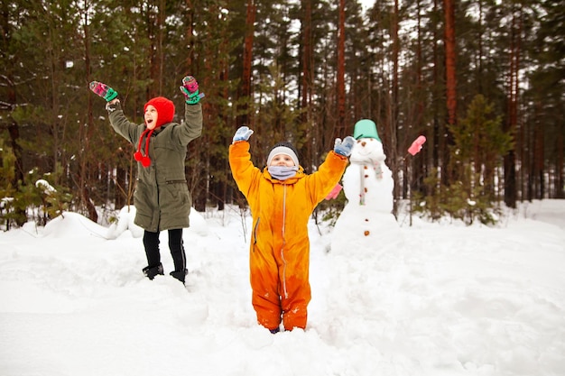 Dos hermanas hacen un muñeco de nieve en invierno