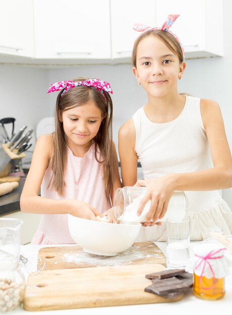 Dos hermanas haciendo masa en la cocina en un tazón blanco grande