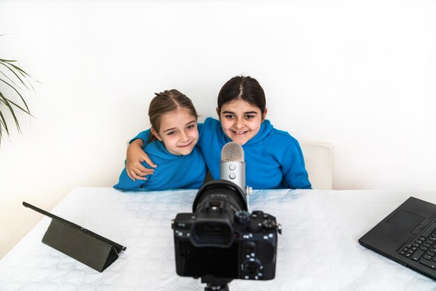 Dos hermanas influyentes y blogueras transmitiendo en vivo desde su sala de estar riendo y mirando a la cámara y hablando por el micrófono en una plataforma de video o red social