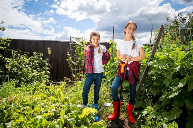 Dos hermanas jóvenes que trabajan en el jardín del patio trasero en un día soleado