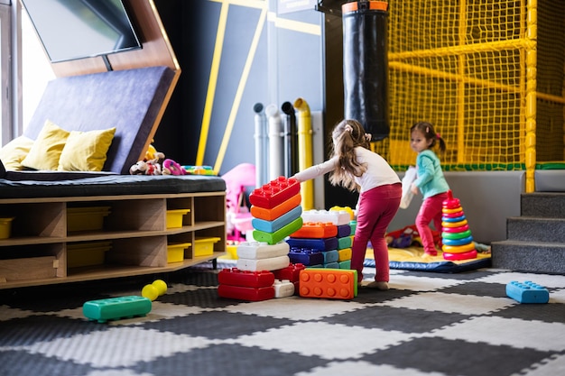 Dos hermanas jugando en el centro de juegos para niños mientras construyen con bloques de plástico de colores